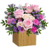 Pink and purple flower arrangement in a wooden cube vase