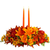 Orange floral centerpiece with two lit taper candles
