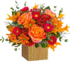 Orange and pink floral arrangement in a wooden cube vase