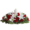 Red roses and white lilies arranged around a lit white candle