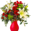 Red and white floral arrangement in a red vase with pinecones