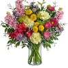 Mixed bouquet of pink, yellow, purple, and white flowers in a clear glass vase
