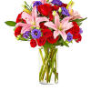 Bouquet of red roses, pink lilies, and purple flowers in a clear glass vase