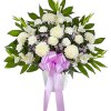 White floral arrangement with a pink ribbon in a vase