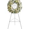 White floral wreath on a black easel stand