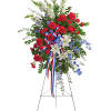 Standing floral spray with red carnations, white lilies, and blue accents on an easel