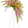 Pink and yellow floral spray on a white easel stand