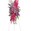 Tall pink and purple floral standing spray on a white easel
