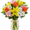 Bouquet of yellow lilies, orange roses, and white daisies in a glass vase