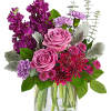 Pink roses and purple flowers in a clear glass vase