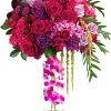 Pink and purple rose arrangement in a tall clear vase with orchids