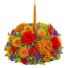 Colorful floral centerpiece with a tall gold candle in the middle