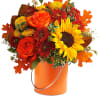 Orange and red bouquet with sunflowers and roses in an orange bucket