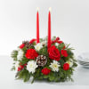 Holiday centerpiece with red candles, roses, carnations, and pinecones