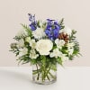 White roses and blue flowers in a clear glass vase