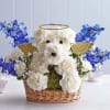 White floral dog arrangement in a wicker basket with blue flowers and gold wings