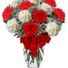 Red and white carnations in a clear glass vase with a red ribbon