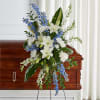 White lilies and blue flowers arranged on a casket