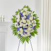 Standing floral wreath of white and purple flowers on an easel