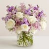 Bouquet of white roses and pink-purple flowers in a clear glass vase