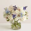 White and blue mixed bouquet in a clear glass vase