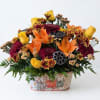 Autumn floral arrangement with orange lilies and yellow roses in a pumpkin-decorated container