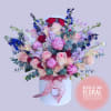 Bouquet of pink and red roses with blue flowers in a white hatbox