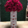 Bouquet of deep pink roses in a tall white vase with lip prints