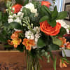 Bouquet of orange roses, white flowers, and orange alstroemeria in a glass vase