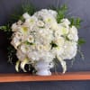 White floral arrangement in a white vase with roses and mums
