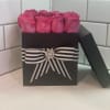Pink roses in a black gift box with a striped ribbon
