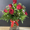 Red roses arranged in a glass vase with a red ribbon