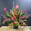 Tropical floral arrangement with orchids and pink blooms in a black vase