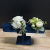 Two white floral corsages on a blue velvet stand
