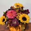 Ceramic pumpkin filled with a collection of fall flowers and foliage.