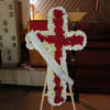 Cross-shaped floral tribute of red and white flowers on an easel