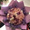 Large bouquet of pastel roses wrapped in pink paper with purple accents