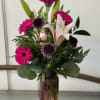Pink gerbera and lily arrangement in a tall vase with a small bird ornament