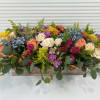 Colorful flower arrangement in a long rectangular wooden box.