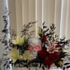 Floral arrangement with red and white flowers around a silver skull centerpiece
