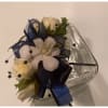 White rose corsage with navy ribbon on a clear tray