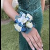 White corsage with blue ribbon on a person's wrist