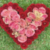 Heart-shaped rose arrangement in pink and red with butterfly accents