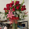 Tall bouquet of red roses and pink lilies in a clear glass vase
