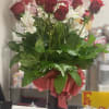 Red roses and white alstroemeria in a black vase with a pink ribbon