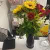 Bouquet of red roses, sunflowers, and white alstroemeria in a dark vase