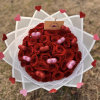Round bouquet of red roses with heart decorations and white wrap