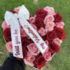 Heart-shaped bouquet of red and pink roses with white ribbons