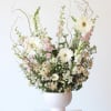 Tall bouquet of white and pink flowers in a pale vase