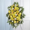 Tall yellow and white standing spray of lilies, roses, and carnations on an easel